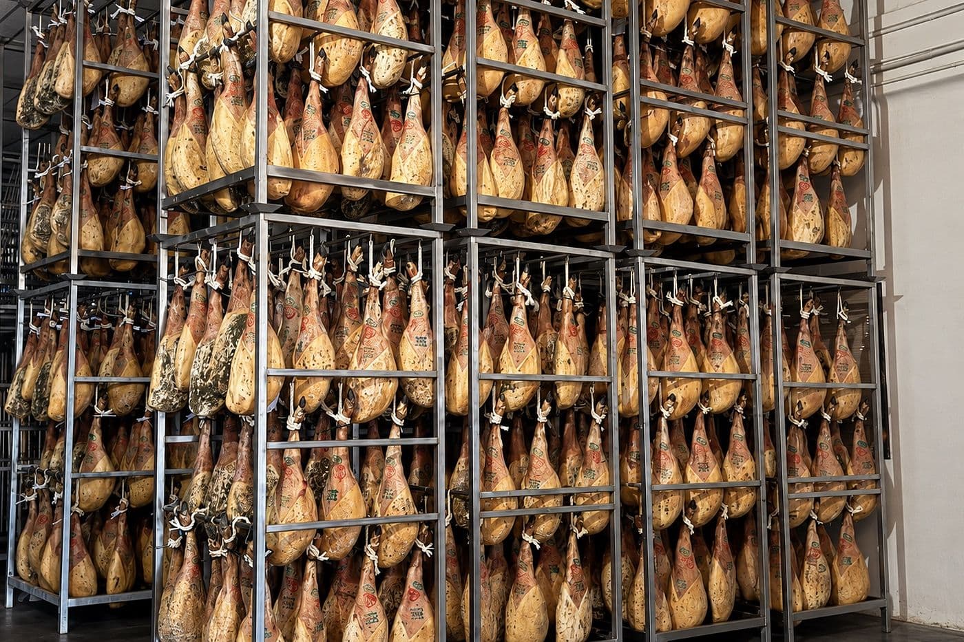 Bodega de afinamiento con bastidores de jamones en penumbra