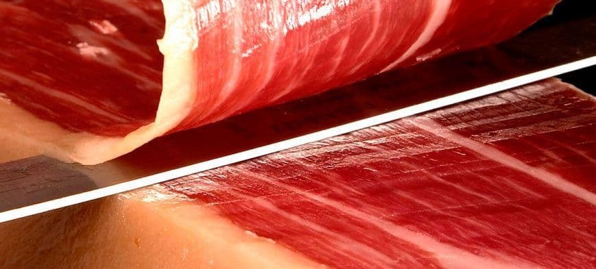 Cuchillo jamonero cortando lonchas finas de jamón ibérico