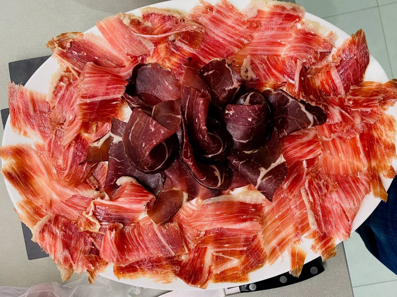 Plate with beef cecina in the centre and sliced Iberico ham around it.